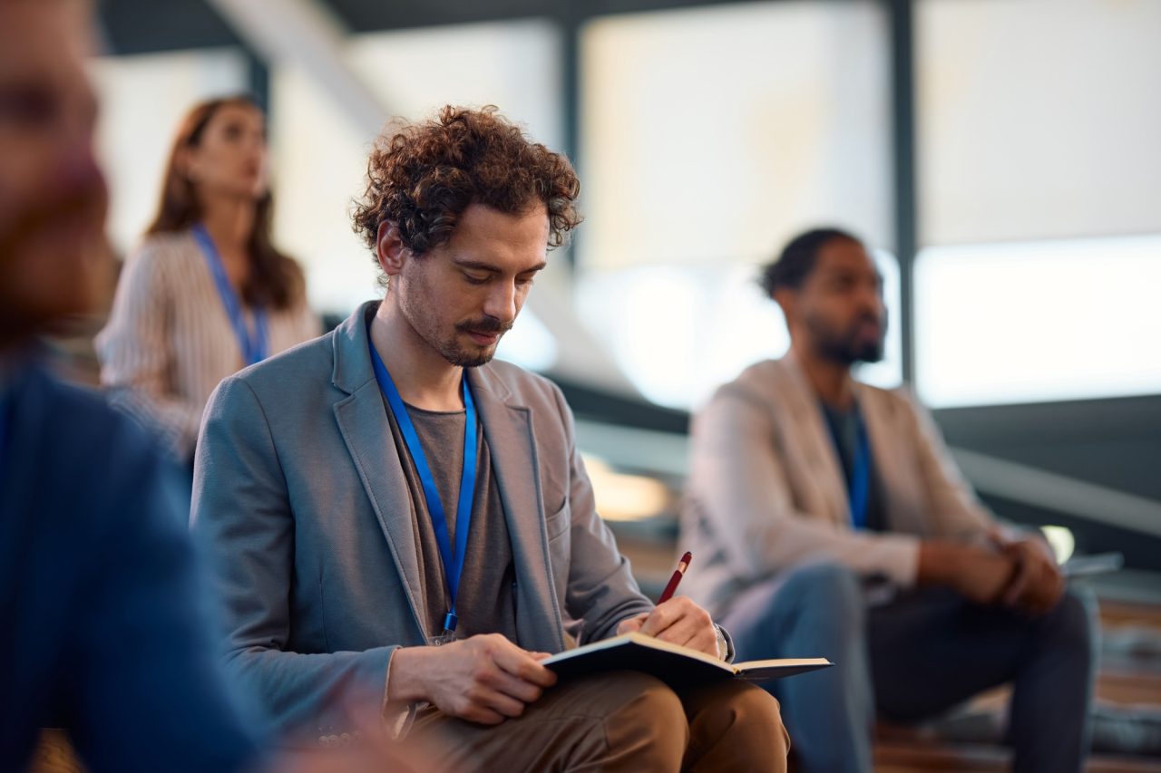 businessman-writing-in-notebook-while-participating-in-education-event-at-convention-center-.jpg